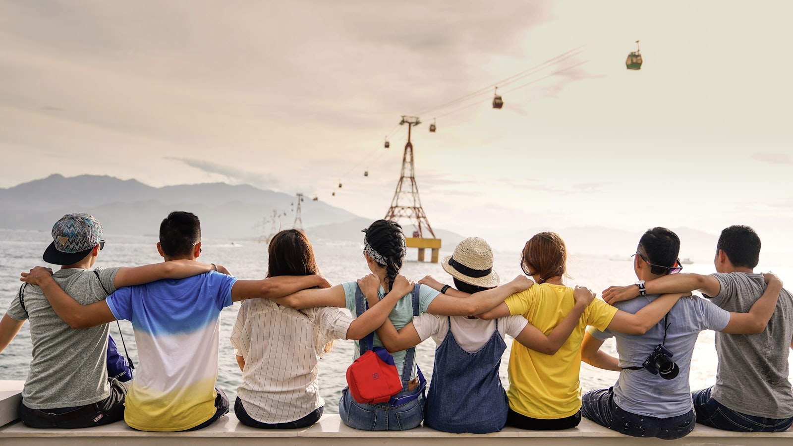 A diverse group of friends sitting arm in arm, looking out at the water